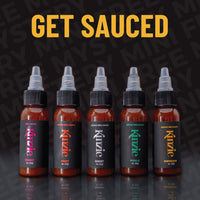 Five bottles of Kuzie sauce with colorful labels on a dark background, featuring the text 'GET SAUCED'.